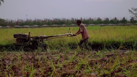 Indonesian-farmer-with-machinery-working-on-rice-field-to-plow-the-field---Indonesian-farmer