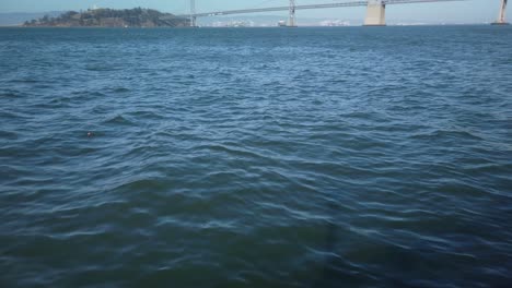 Gimbal-shot-tilting-up-to-the-Bay-Bridge-in-San-Francisco,-California-in-slo-mo