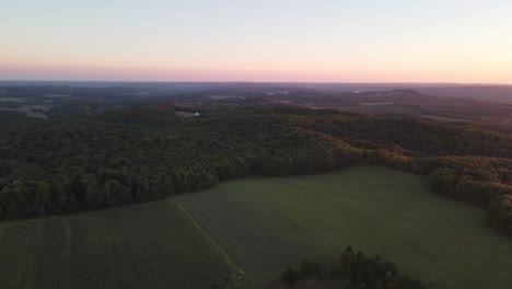Aerial-view-of-the-misty-hills-at-sunset-near-the-famous-Sleeping-Bear-Dunes,-scenic-M22-drive,-and-National-Lakeshore