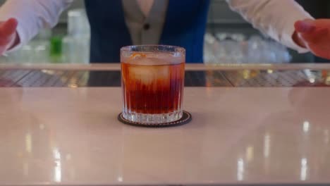 Der-Barkeeper-Serviert-Ein-Cocktail-Mit-Orange-Und-Eis