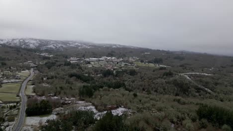 Snowy-village-with-vegetation-in-winter-under-a-cloudy-sky-in-Picornio,-in-Galicia