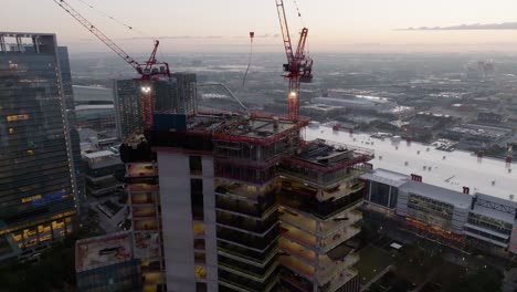 Aerial-view-around-a-skyscraper-construction-site,-dawn-in-Houston,-USA---circling,-drone-shot