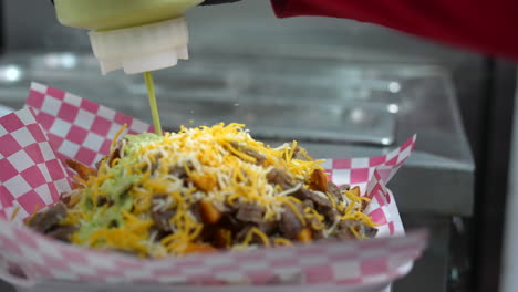 Squirting-guacamole-salsa-sauce-to-carne-asada-smothered-fries---food-truck-series