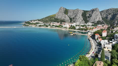 Aerial-views-over-Omis-with-cars-driving-along-the-coastline,-Croatia