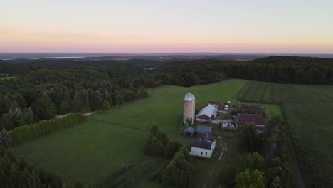 Ascending-aerial-shot-of-a-farm-in-low-rolling-hills-near-Traverse-City-Michigan-at-sunset