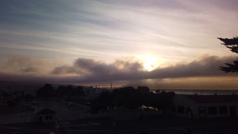Gimbal-static-shot-of-fog-rolling-over-the-Golden-Gate-Bridge-from-Fort-Mason-at-sunset-in-San-Francisco,-California