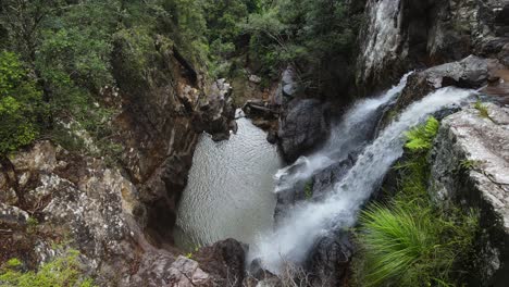 Twin-waterfalls-cascading-down-an-old-growth-rainforest-into-a-natural-rock-formation-swimming-hole