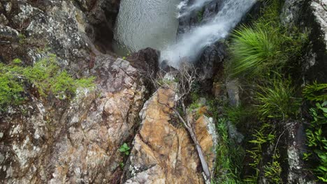 Slow-reveal-of-water-cascading-down-a-rock-formation-into-a-secluded-natural-swimming-hole