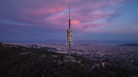 Torre-de-Collserola-communications-tower-at-sunset-on-Tibidabo-with-Barcelona-city-in-background,-Spain