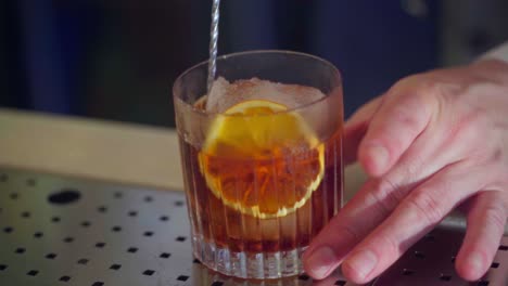 Stirring-gently-a-cocktail-with-ice-and-an-orange-slice