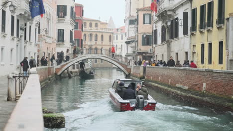 Small-motor-boat-passing-through-small-Venetian-canal