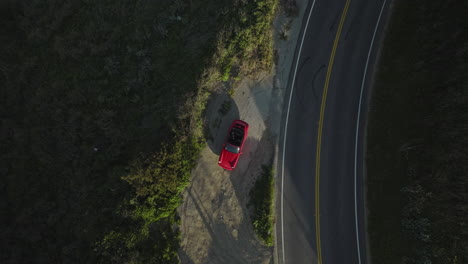 Aerial-drone-shot-rises-up-and-rotates-top-down-over-a-red-Porsche-1993-Carrera-S-near-a-canyon