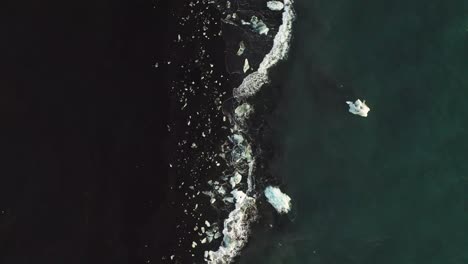 Ocean-Waves-Splashing-On-Shore-Of-Black-Diamond-Beach-In-Iceland---aerial-top-down