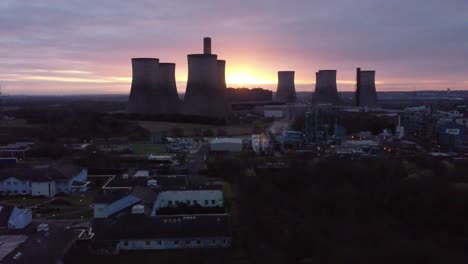 Fiddlers-Ferry-disused-coal-fired-power-station-with-sunrise-horizon-behind-landmark,-Aerial-view-descending