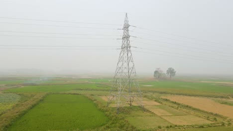High-voltage-electric-lines-crossing-a-foggy-farmland,-a-stark-contrast-of-modern-technology-against-the-natural-landscape
