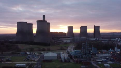 Fiddlers-Ferry-disused-coal-fired-power-station-at-sunrise-behind-landmark,-Aerial-zoom-out-view