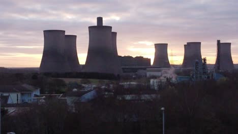 Fiddlers-Ferry-coal-fired-power-station-with-sunrise-behind-landmark,-Aerial-view-orbiting-low-above-trees