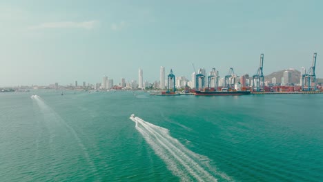 Aerial-Drone-shot-of-a-boat-sailing-near-the-port-and-the-city,-Colombia-Cartagena