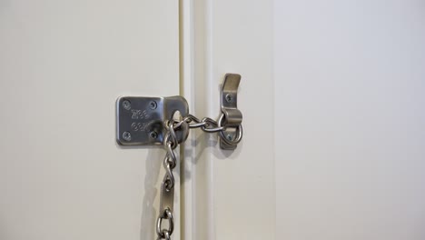 Male-hands-locking-a-door-chain-lock