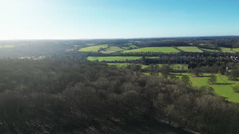 Flying-over-woods,-sheep-fields-and-a-road-in-the-Great-Missenden-countryside