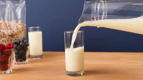 Pouring-a-glass-of-milk-from-a-pitcher,-making-breakfast