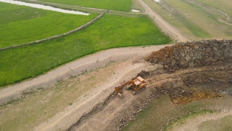 Industrial-excavator-tearing-up-farmland,-destroying-fertile-soil-in-the-process,-a-sad-reality-of-land-degradation-and-destruction