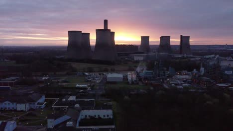 Fiddlers-Ferry-disused-coal-fired-power-station-at-sunrise-glowing-behind-Warrington-landmark,-Aerial-view