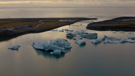 Toma-Aérea-De-Camiones-De-Icebergs-De-Jokulsarlon-Y-El-Océano-En-El-Fondo-Durante-La-Puesta-De-Sol-En-Islandia