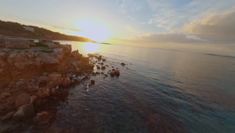 FPV---Flying-over-Kavouri-Beach-in-Vouliagmeni,-Greece-at-sunset