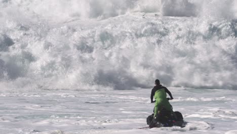 Jetski-driver-and-a-surfer-trying-to-ride-the-choppy-waves-full-of-white-foam-Nazare,-Portugal