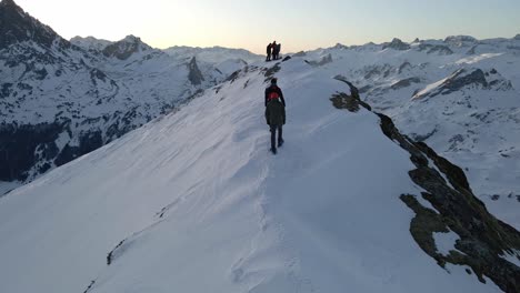 Drone-footage-turning-around-of-three-people-walking-on-a-snowy-crest-with-snowshoes-near-the-Pic-du-Midi-D'Ossau