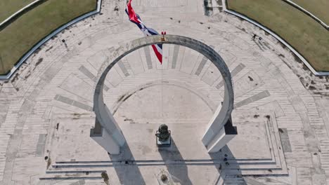 Fpv-Aerial-top-down-shot-of-waving-flag-of-Dominican-Republic-on-Memorial-at-Plaza-de-la-Bandera
