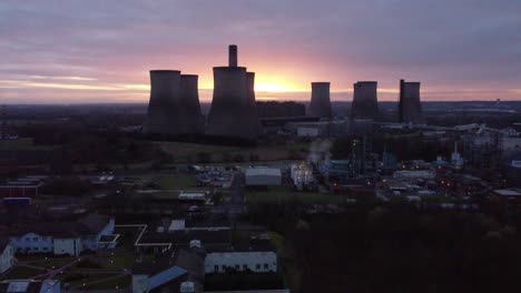 Fiddlers-Ferry-disused-coal-fired-power-station-at-sunrise-glowing-behind-Warrington-landmark,-Aerial-view-orbit-right
