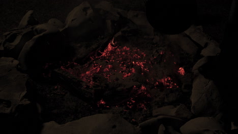 Slow-motion-of-campfire-in-stone-fire-pit-being-put-out-with-sand-and-bucket