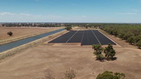 Aerial-view-of-solar-farm-beside-an-irrigation-canal-on-a-traditional-farm-in-Australia