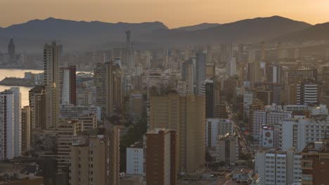 Aerial-panning-view-of-city-skyline-Benidorm-with-tall-vacation-building-at-sunset