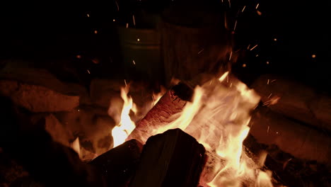 Slow-motion-close-up-of-crackling-campfire-being-tended-to-and-embers-flying-off