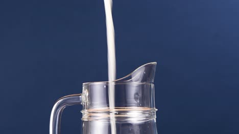 Studio-shot-of-milk-being-poured-down-into-a-big-pitcher