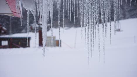 Icicles-growing-from-Roof-in-Winter,-Blurred-Background-of-Winter-Scene