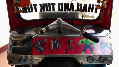 The-inside-of-a-Tuk-Tuk-cockpit-in-Thailand-with-a-Marvel-comic-theme,-slow-motion