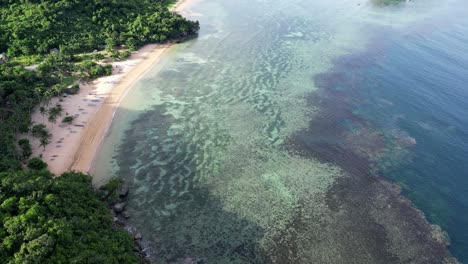 Stunning-Aerial-view-of-Coastal-Reef-under-clear-Oceans-Waves-next-to-white-sand-beach-in-Catanduanes,-Philippines