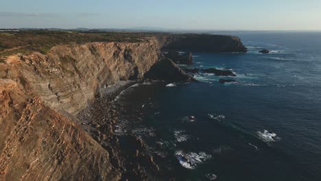 Drone-shot-of-Portuguese-cliffs-washed-by-waves-off-the-Atlantic-Ocean-on-a-sunny-day