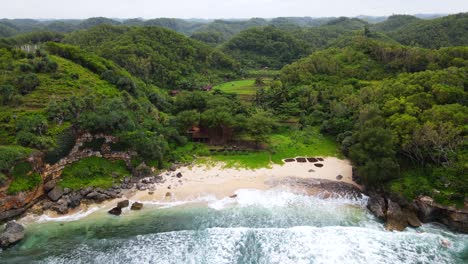 Drohnenaufnahme-Eines-Privaten-Tropischen-Strandes-Mit-Weißem-Sand,-Umgeben-Von-Wald-Und-Hügeln-–-Indonesien