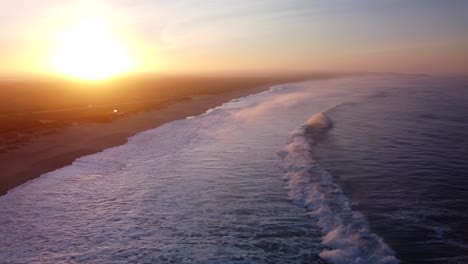 Aerial-view-of-waves-reaching-shoreline-of-supertubos-beach-during-golden-sunset-in-Portugal