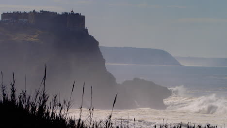 Welle-Bricht-Gegen-Die-Klippe-In-Nazare,-Portugal-Unterhalb-Des-Leuchtturms