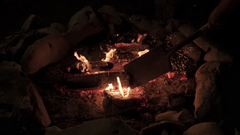Slow-motion-of-shovel-putting-out-campfire-in-stone-ring