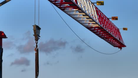 Fast-paced-aerial-video-of-the-structure-of-a-crane,-a-hook-hangs-from-its-arm-and-chains-hang-from-the-arm