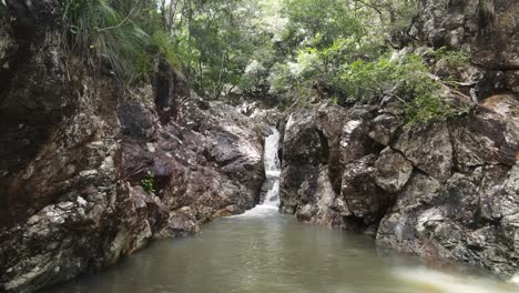 Tropical-rainforest-creek-flowing-into-a-secluded-private-rock-swimming-hole