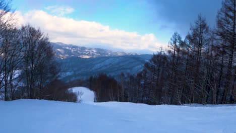 Going-down-hill-on-ski-slope,-first-person-view-with-Hida-Mountains-in-Background,-Japan