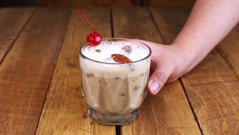 Closeup-of-hand-rotating-a-kahlua-base-cocktail-with-coffee,-alcohol-and-milk-on-a-wooden-table
